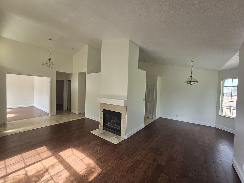 Living room with fireplace and solid oak floors. Kitchen is to the right, the entry, den, and bedroom is to the left
