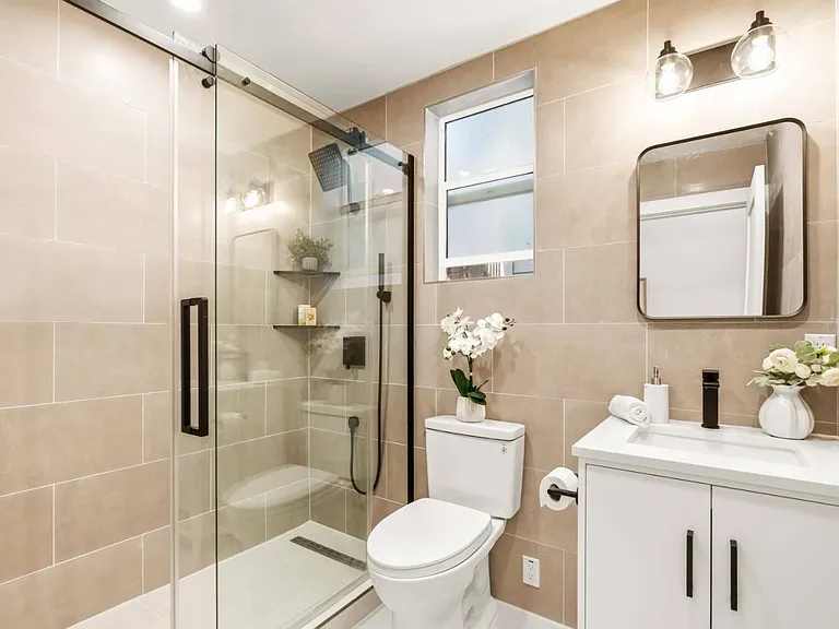 Brand new bathroom with large shower, exhaust vent and bright lighting