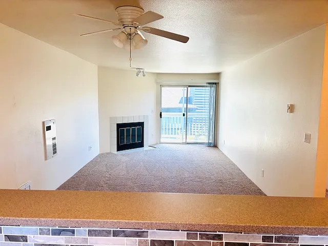 Open floorplan view from kitchen, through to fireplace next to sliding door to balcony. Dining room ceiling in foreground.