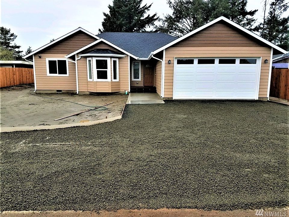 Front of home with wide gravel driveway that will be black tomorrow and wraps around from the sidewalk to the left end of the pr