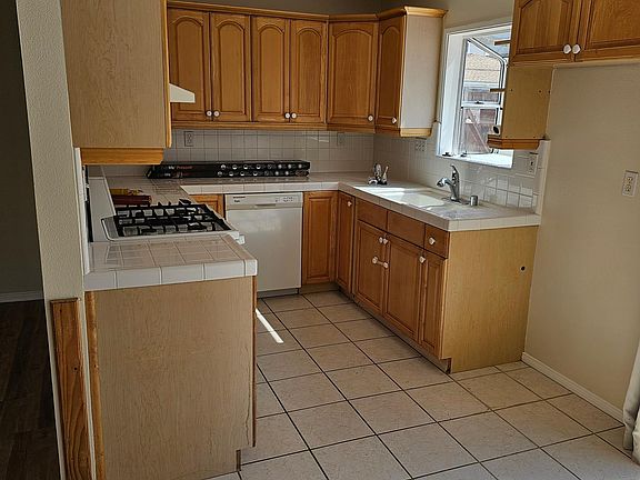 View of the kitchen. Note the maple-faced cabinets, dishwasher, gas range, and garden window.