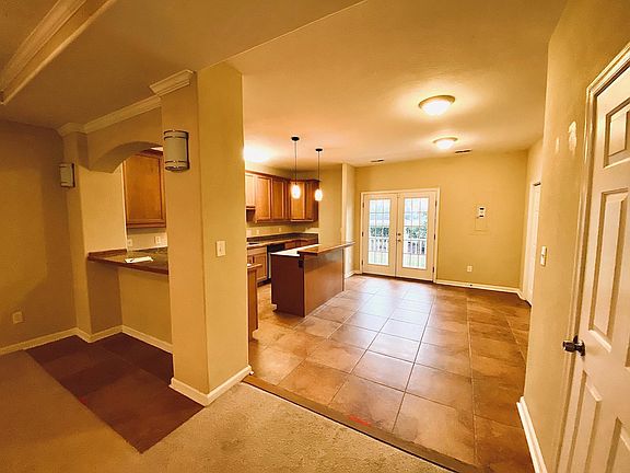 View of kitchen, living room bar seating, kitchen bar seating, dining area, and exit to the 1st-floor exterior patio.