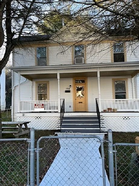 Street side view with large front porch and fenced in yard.