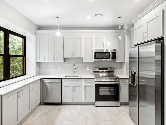 Kitchen featuring new quartz countertops, and brand new stainless steal appliances including dishwasher, oven, microwave and refrigerator.