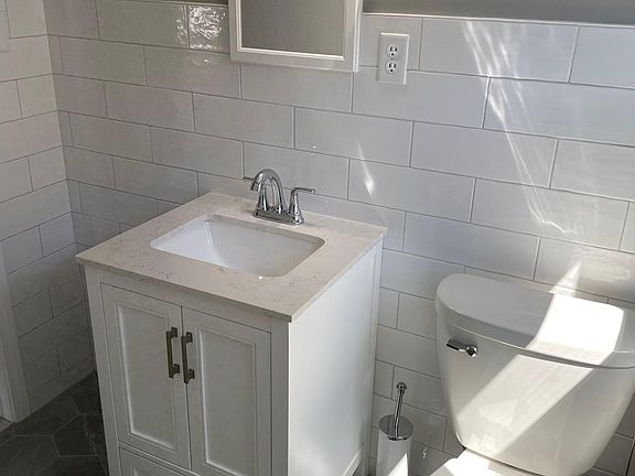 Completely renovated bathroom with ceramic tile on all walls. New vanity, toilet, tub and fixtures