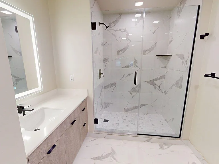 Apartment bathroom with glass-enclosed shower, wood-style flooring, double sinks, and LED vanity mirror.
