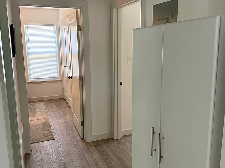 Hallway leading to second and third bedrooms and bathroom with linen cabinet.