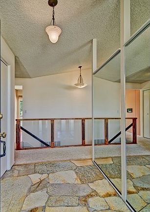 Wide entry hall with vintage stone floor, mirrored wall and an a
