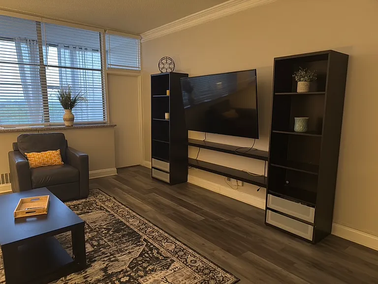Spacious Living & Entertainment Area
Enjoy a comfortable living space featuring modern wood-style flooring, large windows, and a dedicated entertainment area with built-in-style shelving.