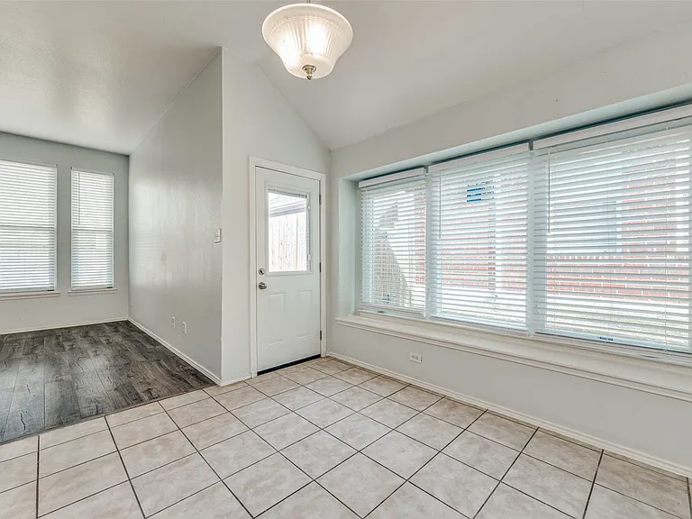 Spacious room featuring a combination of light-toned tile flooring and dark wood-finish flooring