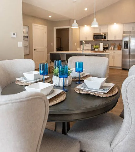 Interior of Champion Reserve Townhomes dining area with kitchen and breakfast bar in the background.
