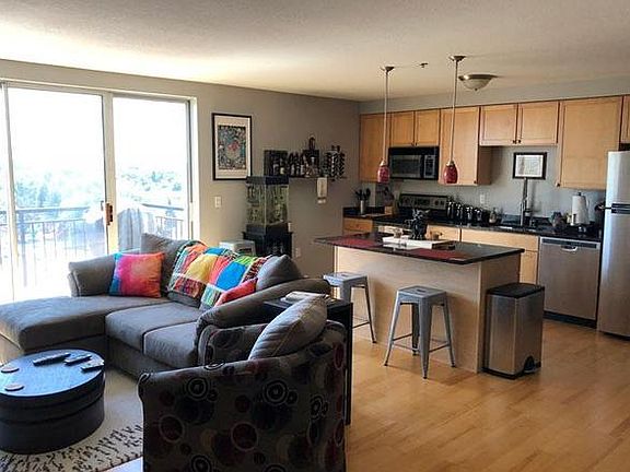 Bright, open living room and kitchen featuring hardwood floors and granite countertops.