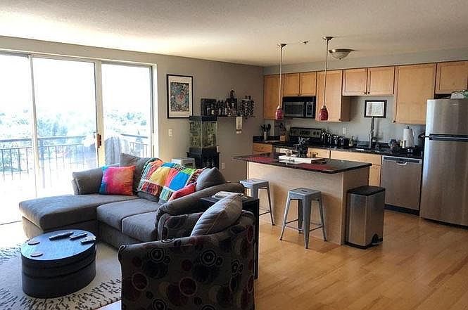 Bright, open living room and kitchen featuring hardwood floors and granite countertops.