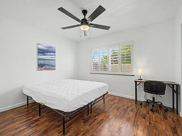 Wood flooring, Queen Bed, desk, chair, lamp, fan, mirrored closet.