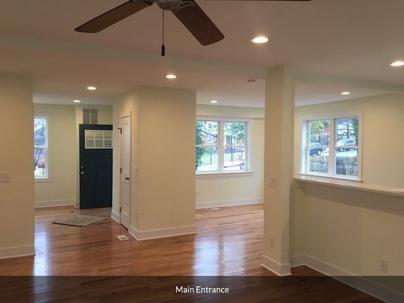 Living room looking at main interior entrance and dining room flanked with windows. Half Bath is in the center.