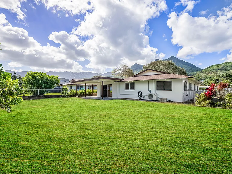Huge fully fenced back yard with covered lanai showing mountain view in front of house.