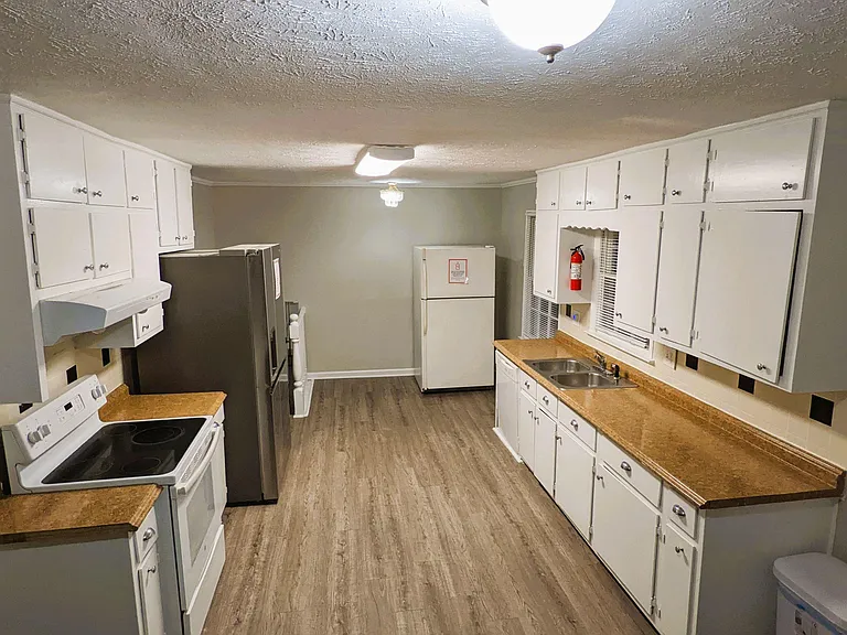 Galley-style kitchen with ample cabinet storage, laminate countertops, and a double-basin sink plus full-size appliances.