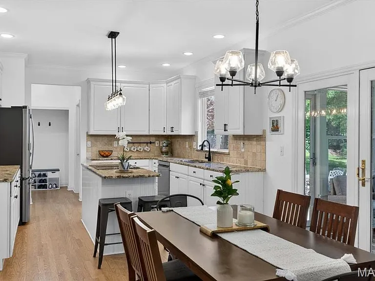 Kitchen and dining area featuring white cabinetry, granite countertops, tile backsplash, and wood-finish flooring