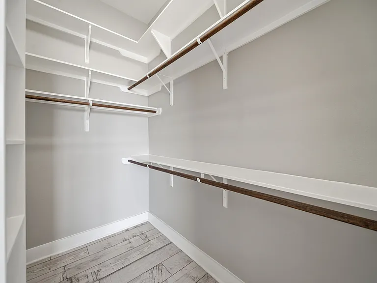 Spacious secondary walk-in closet in the primary suite, thoughtfully designed with multiple shelving units and hanging rods for maximum storage and organization.