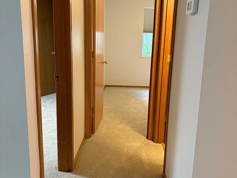 Hallway with primary bedroom on left, bedroom #2 straight ahead and bathroom on the right.