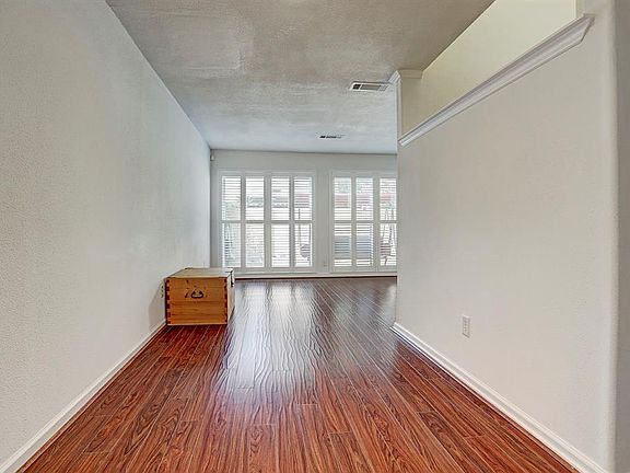 View through the dining room to the living room showing the stairwell and decorative molding