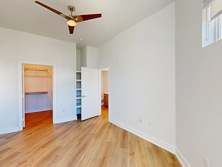 Spacious apartment bedroom with large closet and wood-style flooring.