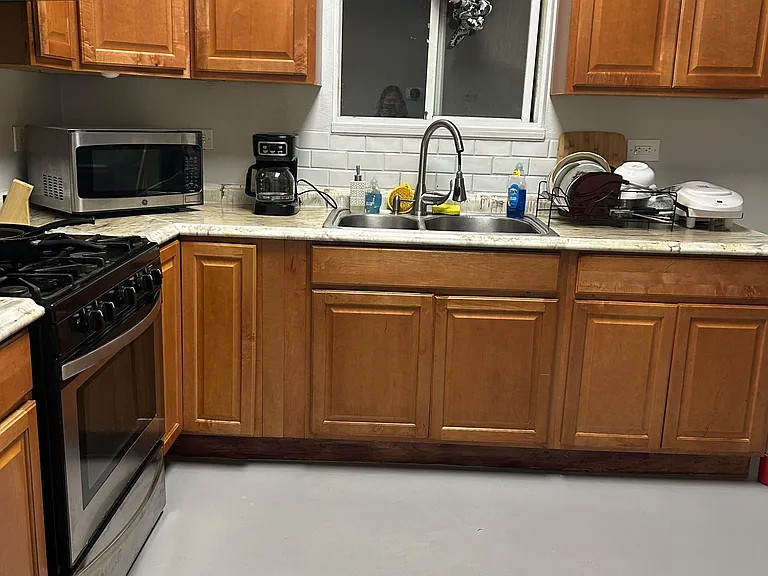 Functional kitchen with ample wood cabinetry, double-basin sink, gas range, and countertop space for meal prep.
