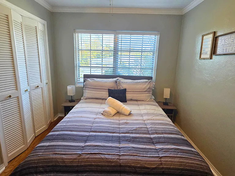 Bedroom with ceiling fan, window and towels set for extra comfort