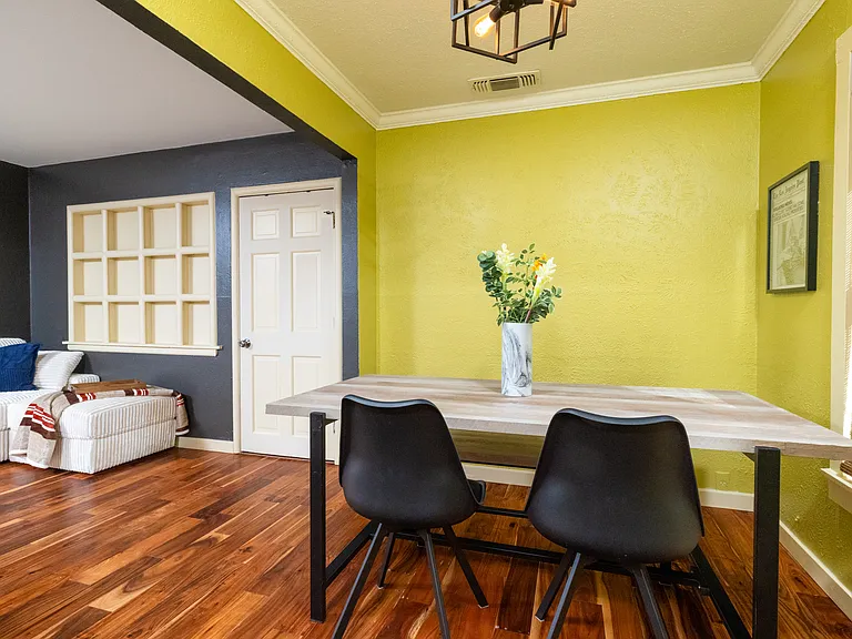Cozy dining nook with a modern farmhouse table, soft lighting, and warm green walls. Perfect for enjoying meals, morning coffee, or working in a relaxed atmosphere.
