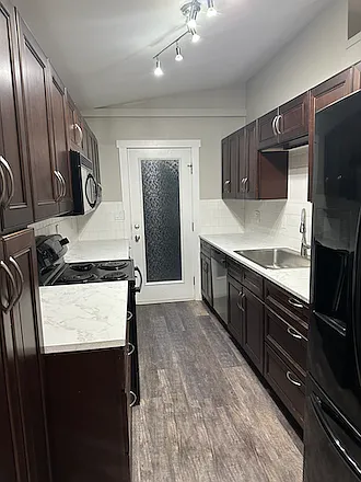 updated kitchen with large singe basin sink, large refrigerator, electric stove/oven, microwave/hood vent that vents to the exterior, dishwasher and lots of cabinet space.
