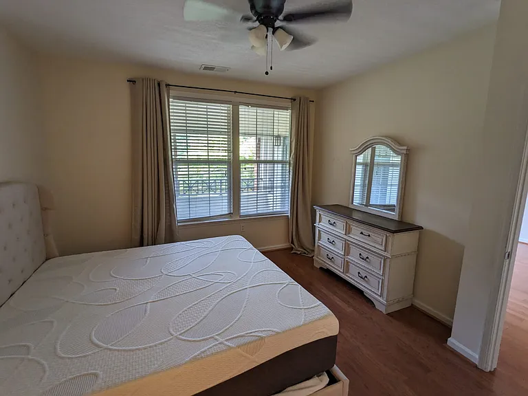 Master bedroom furnished with a king-size bed and a dresser with a mirror