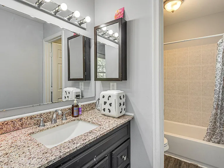 Bathroom features a granite-top vanity with ample counter space, mirrored storage, and a tub/shower with tile surround.