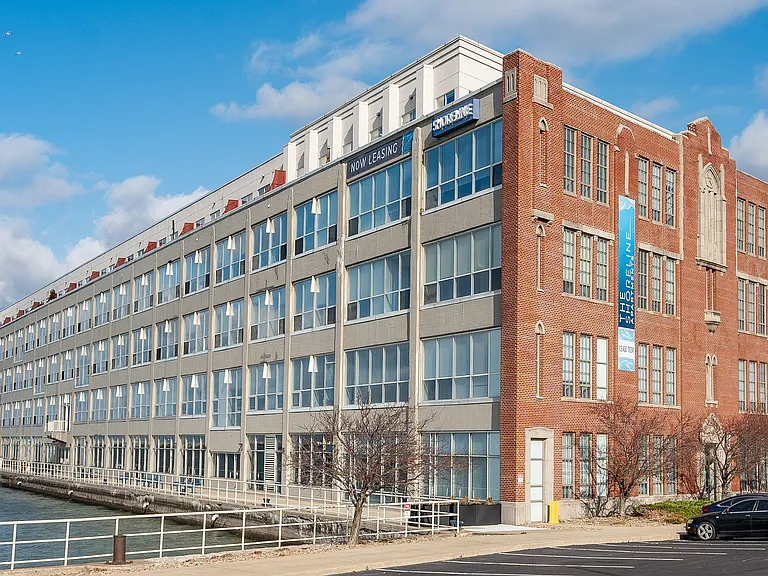 Charming waterfront apartment building with modern design and large windows, offering scenic views and contemporary living spaces.