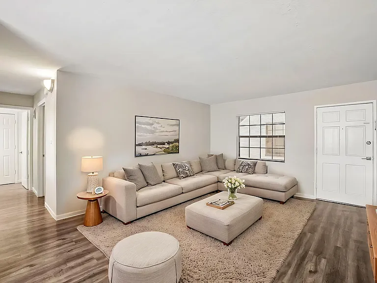 Inviting living room with a cozy beige sectional sofa, chic decor, and warm lighting on elegant wood flooring.