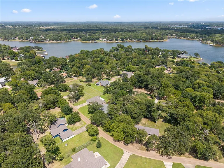 Expansive lakefront community featuring mature trees and a clear blue sky