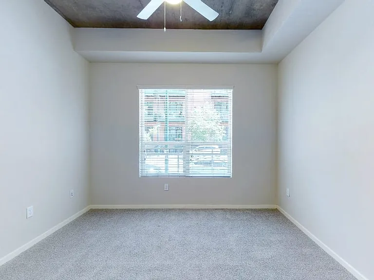 Spacious apartment bedroom with plush carpet flooring.