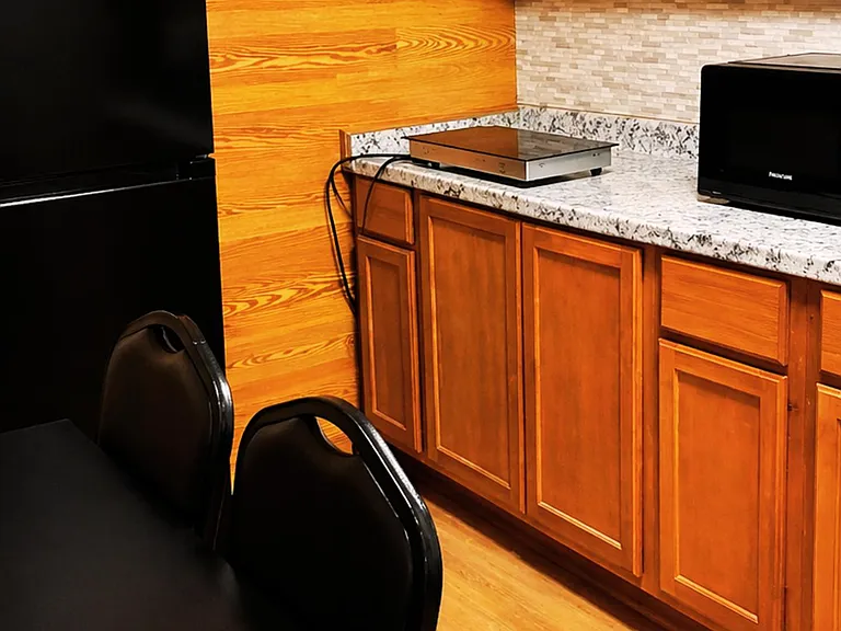 Kitchenette with ample cabinet storage, durable countertops, and convenient microwave and mini fridge for everyday meals.