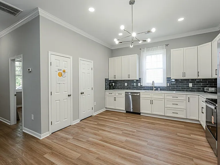 Spacious kitchen with ample white cabinetry, stainless appliances, and a large counter run with window-side sink.
