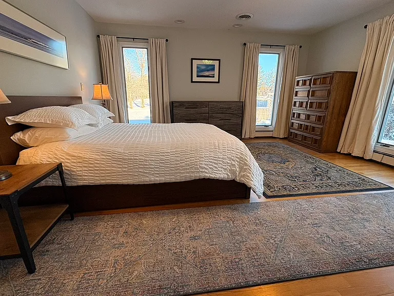 Large bedroom with 3 floor-to-ceiling windows that look out to peaceful, wide open spaces.