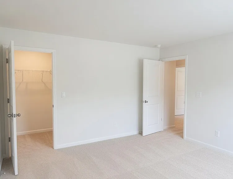 Bright secondary room featuring a large window with plantation shutters, soft carpet, and high ceilings.