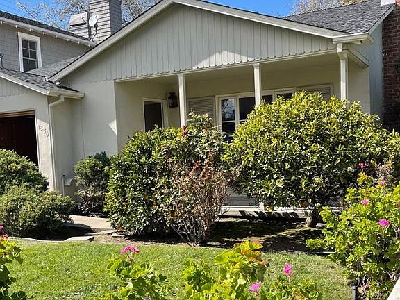 Front of home with lawn, mature landscaping, lemon tree and a front porch for relaxing.