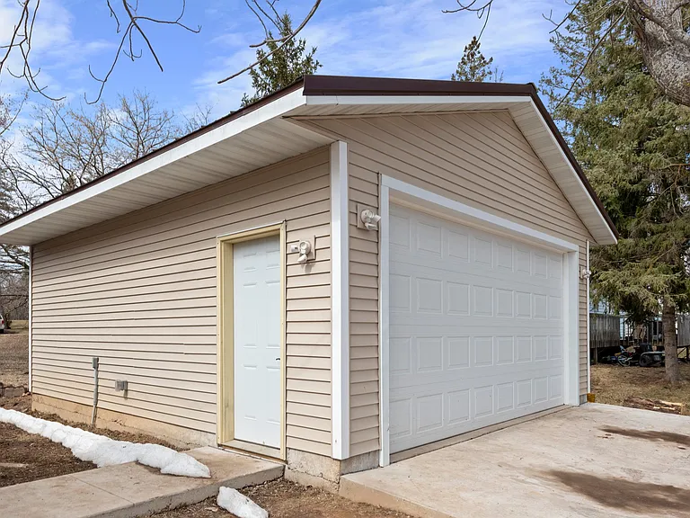 Two car garage with service door. Sidewalk leads to entry.