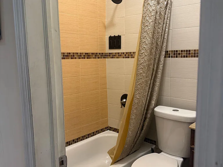 Full bath with shower/tub combo, tile surround, and convenient fixtures for everyday use + window for ventilation & light.