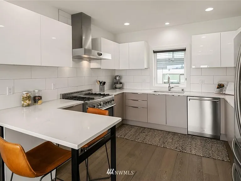 The sleek high-end kitchen features chef's grade stainless steel appliances, marble casual counters, plentiful cabinets and a wine fridge.