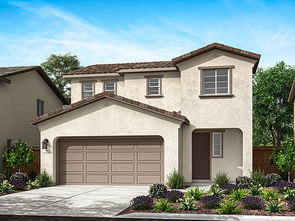 A two-story stucco house with a tiled roof, a garage door, and a well-landscaped front yard with var