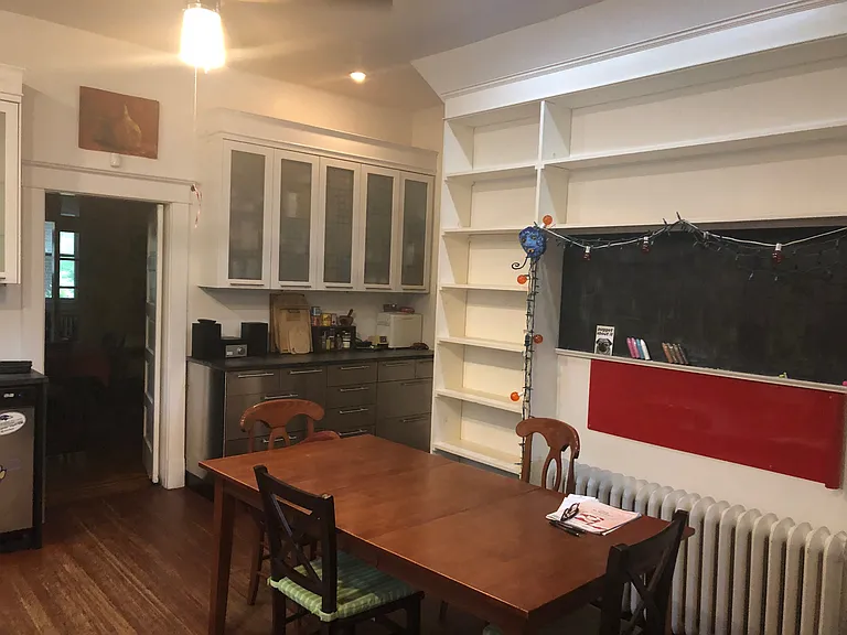 Other side of kitchen. Ample shelving and chalkboard. Ceiling fan. Radiator heat.