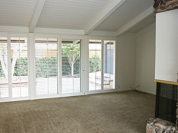 Large living room features wall to wall windows and wooden shutters