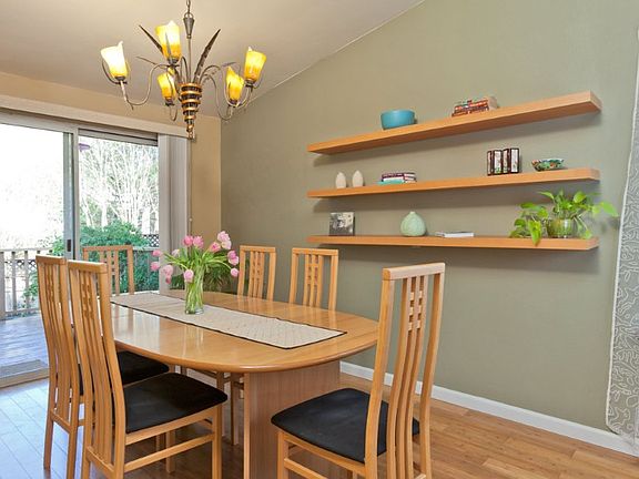 The formal dining room is spacious and light opening to a deck overlooking the back garden. Modern shelving adds display space and the new lighting fixture more style.