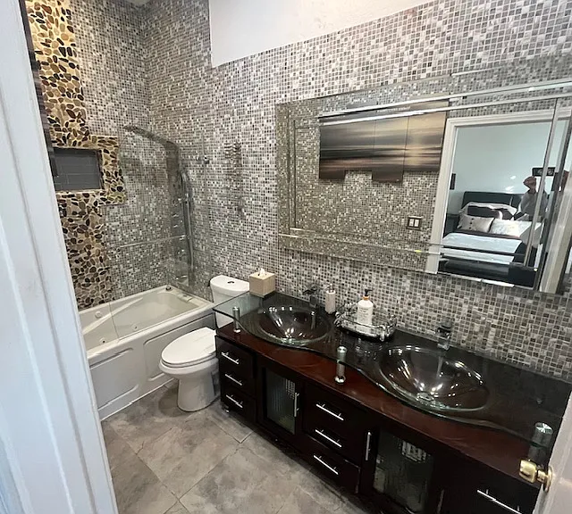 Master ensuite w/fully tiled jetted tub with rainfall shower tower, body massage jets, half panel shower door, double glass top wood vanity