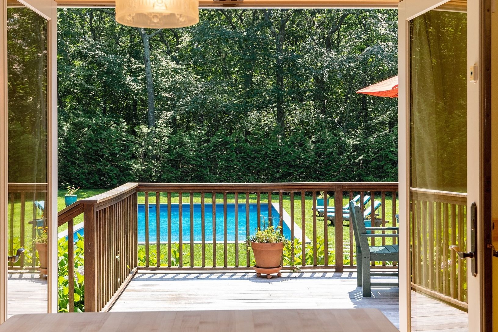  View Through One Of Three Sets Of French Doors Looking Out Onto An Oversized Mahogany Deck 